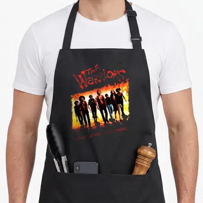 Tablier de cuisine noir avec illustration colorée d'un groupe de sept personnages et texte rouge stylisé en graffiti.