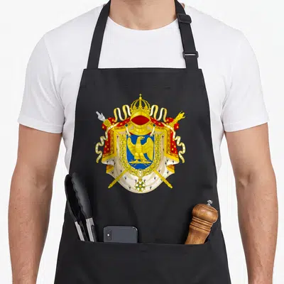 Tablier de cuisine noir avec un grand aigle impérial doré sur fond bleu, entouré d'une couronne et de sceptres rouges.