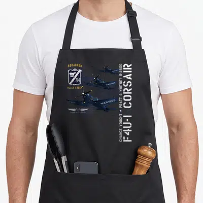 Tablier de cuisine noir avec illustration technique d'un avion Corsaire F4U-1 214 Black Sheep et inscriptions blanches et jaunes.