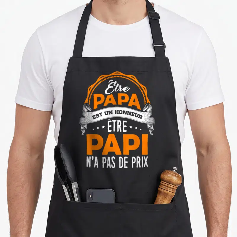 Tablier de cuisine noir avec une inscription orange et blanche célébrant le rôle de grand-père et de père dans un style vintage.
