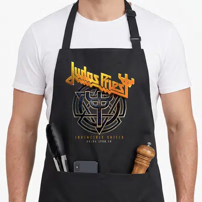 Tablier de cuisine noir avec le logo doré Judas Priest et le symbole Invincible Shield au centre.
