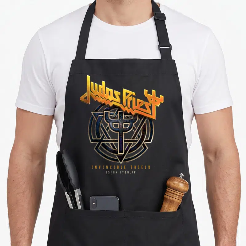Tablier de cuisine noir avec le logo doré Judas Priest et le symbole Invincible Shield au centre.