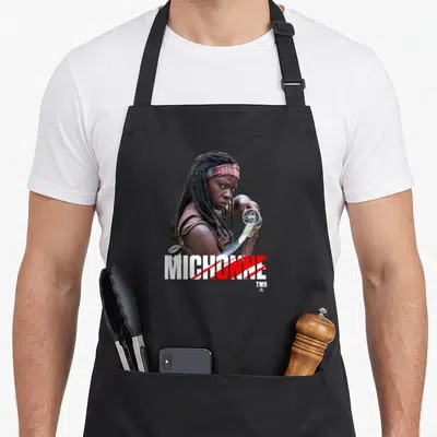 Tablier de cuisine noir avec une illustration de Michonne tenant un katana et son nom imprimé en gros caractères.