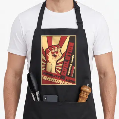 Tablier de cuisine noir avec illustration poing levé rouge et texte Égalité Révolution Communiste sur fond rayé beige.