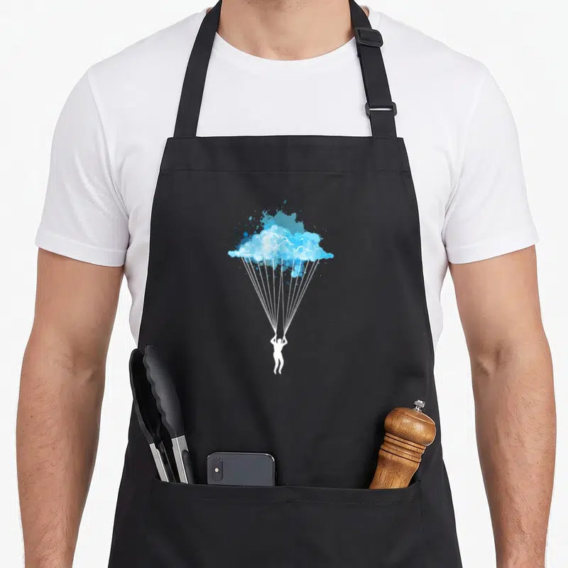 Tablier de cuisine noir avec silhouette blanche accrochée à un parachute nuageux bleu stylisé.