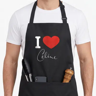 Tablier de cuisine noir avec un grand cœur rouge, la lettre I blanche et le prénom Celine en écriture cursive élégante.