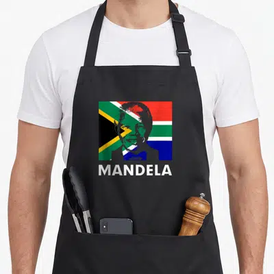 Tablier de cuisine noir avec portrait de Nelson Mandela superposé au drapeau sud-africain et texte MANDELA en blanc.