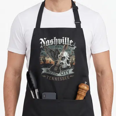 Tablier de cuisine noir avec illustration vintage d'un crâne ailé tenant une guitare et le texte Nashville Music City Tennessee