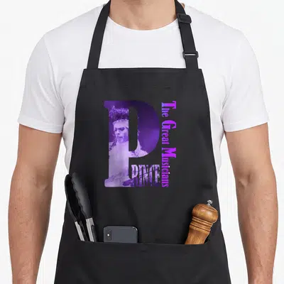 Tablier de cuisine noir avec un grand P violet contenant le portrait de Prince et le texte Les Grands Musiciens.