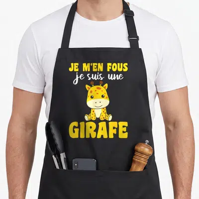 Tablier de cuisine noir avec une illustration de girafe jaune et le texte Je m'en fous je suis une girafe imprimé en lettres jaunes et blanches.