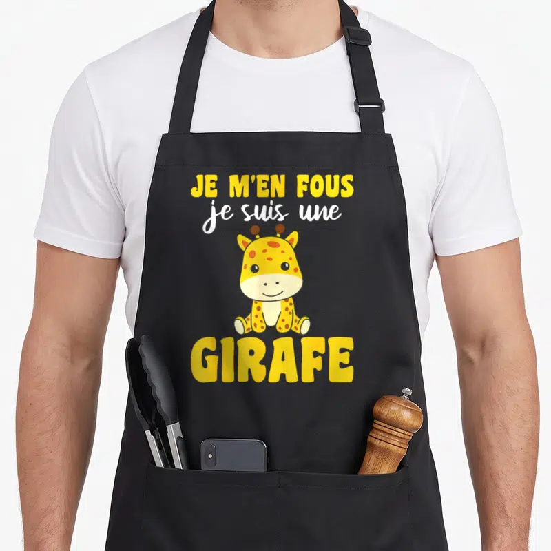 Tablier de cuisine noir avec une illustration de girafe jaune et le texte Je m'en fous je suis une girafe imprimé en lettres jaunes et blanches.