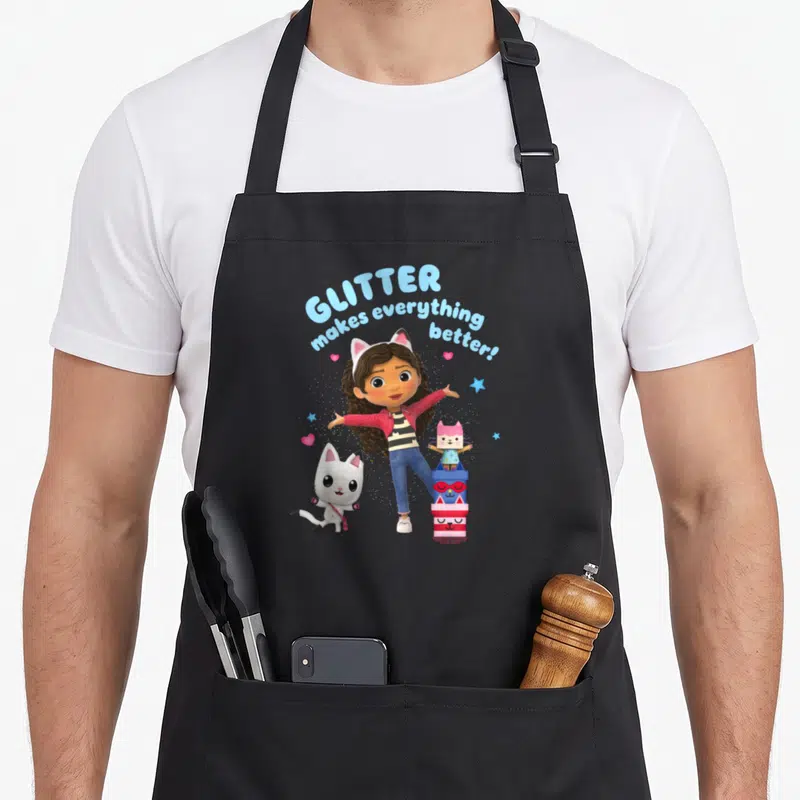 Tablier de cuisine noir avec Gabby, son chat blanc et la phrase Glitter makes everything better en bleu.