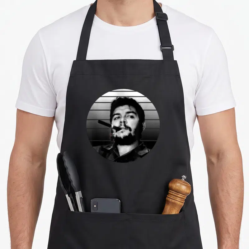 Tablier de cuisine noir avec portrait circulaire de Che Guevara fumant un cigare sur fond de bandes horizontales.