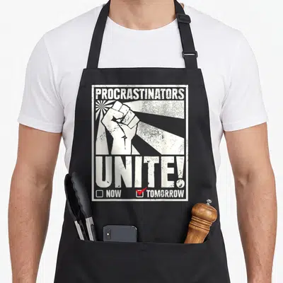 Tablier de cuisine noir avec illustration poing levé et texte Procrastinators Unite Tomorrow en blanc.
