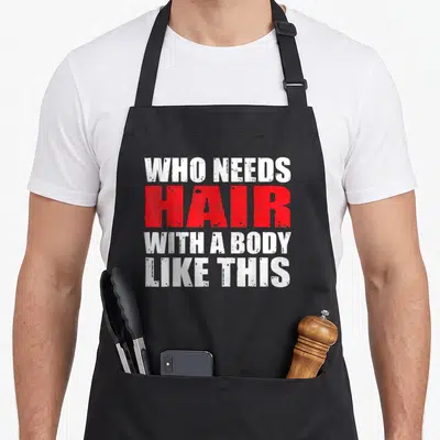 Tablier de cuisine noir avec inscription Who Needs Hair With A Body Like This en blanc et rouge.