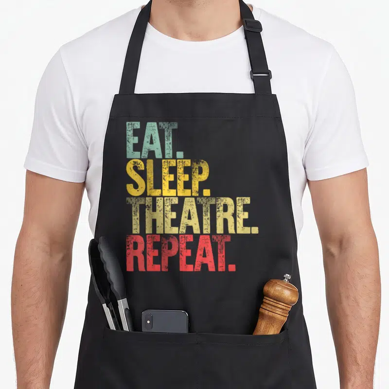 Tablier de cuisine noir avec inscription Eat Sleep Theatre Repeat en lettres colorées style vintage
