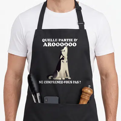 Tablier de cuisine noir avec un loup assis qui hurle et du texte humoristique imprimé en blanc sur le devant.