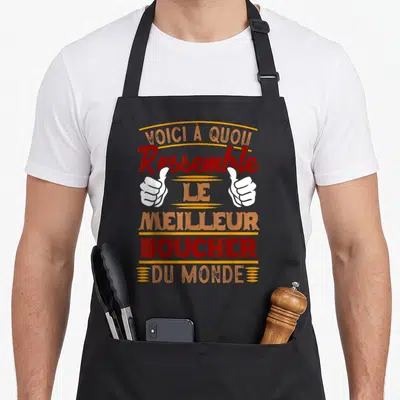 Tablier de cuisine noir avec inscription Ressemble au meilleur boucher du monde et deux mains faisant un signe de pouce levé.