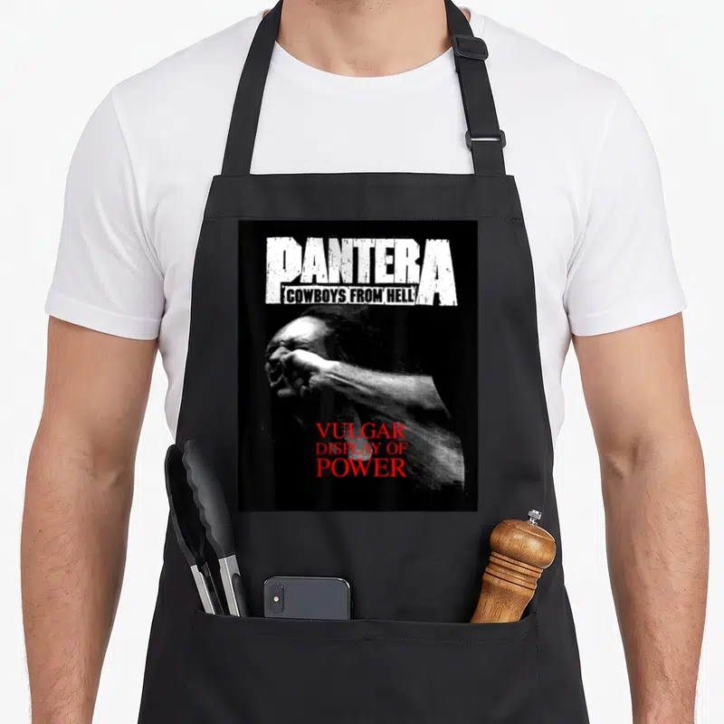 Tablier de cuisine noir avec le logo Pantera, l'inscription Cowboys From Hell et une illustration monochrome avec le titre Vulgar Display of Power en rouge.