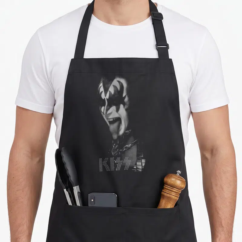 Tablier de cuisine noir avec le portrait en noir et blanc de Gene Noir et Blanc et le logo KISS en pointillés blancs.