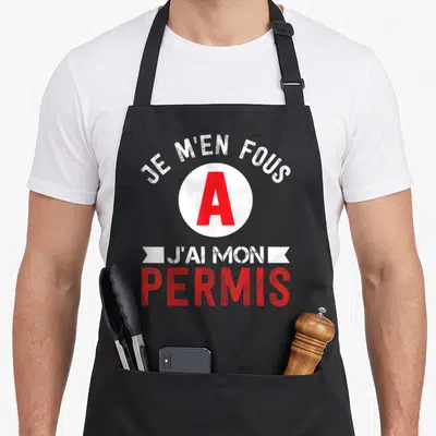 Tablier de cuisine noir avec l'inscription Je m'en fous j'ai mon permis A en blanc et rouge.