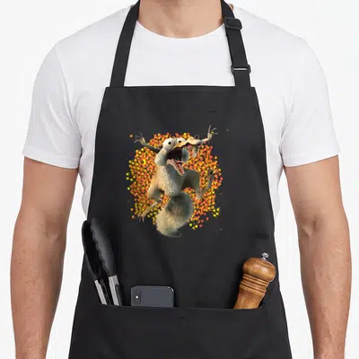 Tablier de cuisine noir avec Scrat en pleine course folle autour d'une avalanche de noisettes colorées.