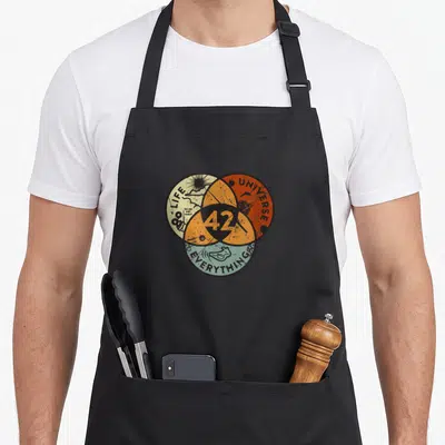Tablier de cuisine noir avec un diagramme de Venn coloré affichant le chiffre 42 au centre des cercles Vie, Univers et Tout.