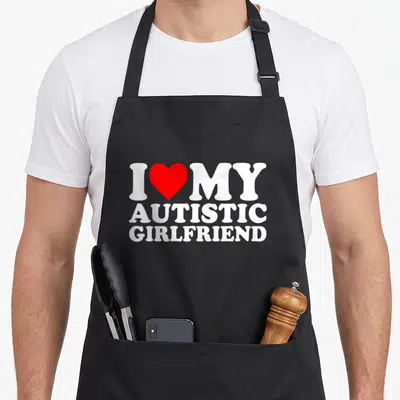 Tablier de cuisine noir avec inscription blanche I Love My Autistic Girlfriend et un cœur rouge au centre du motif imprimé.