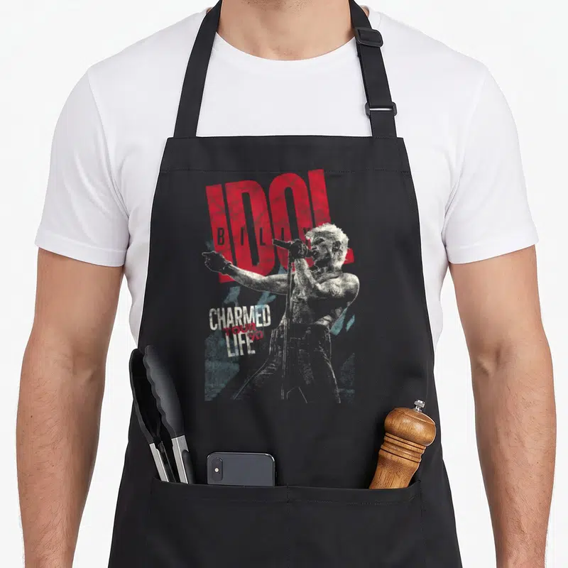 Tablier de cuisine noir avec illustration de Billy Idol tenant un micro et texte rouge IDOL Charmed Tour Life.