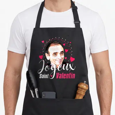 Tablier de cuisine noir avec portrait souriant, cœurs roses et texte Joyeux Saint Valentin en calligraphie blanche et rose.