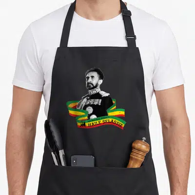 Tablier de cuisine noir avec portrait de Haile Selassie et drapeau éthiopien en ruban coloré.