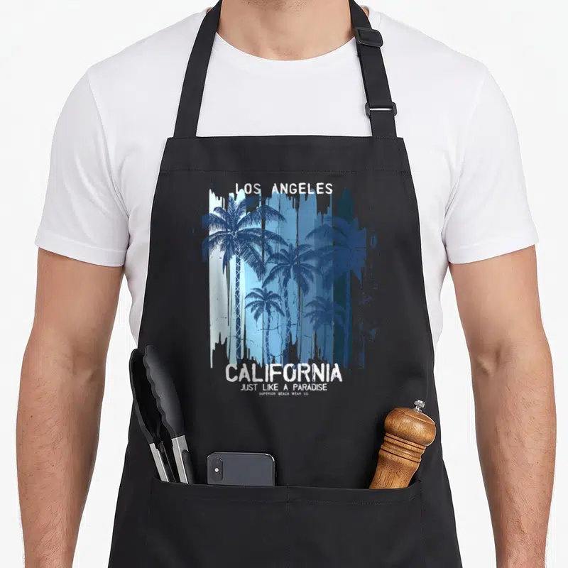 Tablier de cuisine noir avec illustration palmiers bleus et texte Los Angeles California Just Like A Paradise en blanc.