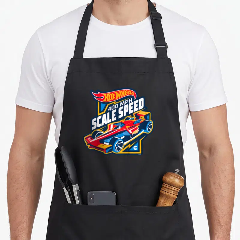 Tablier de cuisine noir avec le logo Hot Wheels, l'inscription Scale Speed et une monoplace rouge et bleue stylisée.