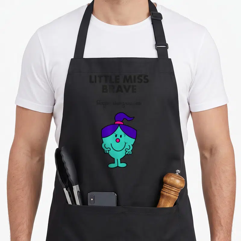 Tablier de cuisine noir avec illustration colorée de Little Miss Brave aux cheveux violets et corps turquoise.