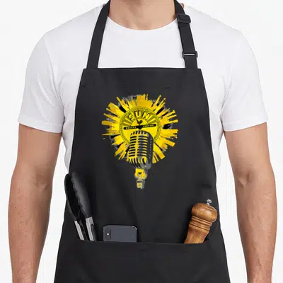 Tablier de cuisine noir avec illustration microphone vintage et logo circulaire Sun Record Company sur éclaboussure jaune vif.