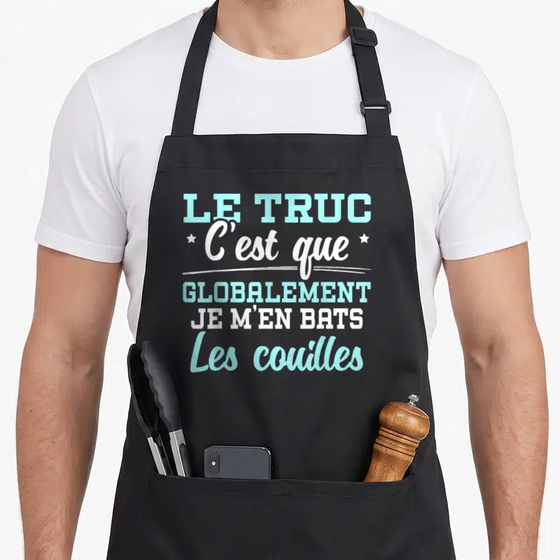 Tablier de cuisine noir avec l'inscription Le Truc C'est Que Globalement Je M'en Bats Les Couilles en bleu et blanc.