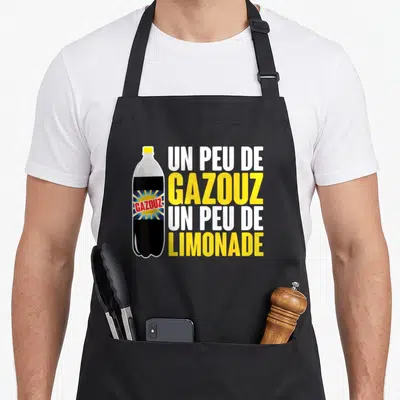 Tablier de cuisine noir avec illustration de bouteille de Gazouz et texte Un peu de Gazouz un peu de Limonade en blanc et jaune.