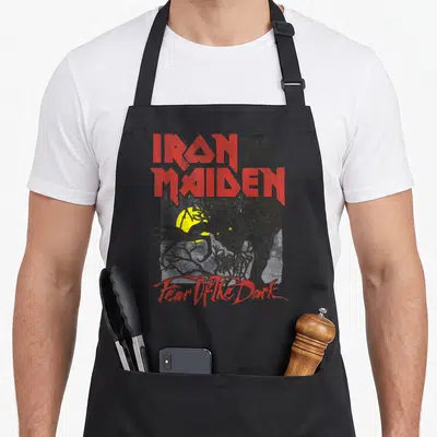Tablier de cuisine noir avec le logo Iron Maiden rouge et une illustration de monstre jaune sous la lune.