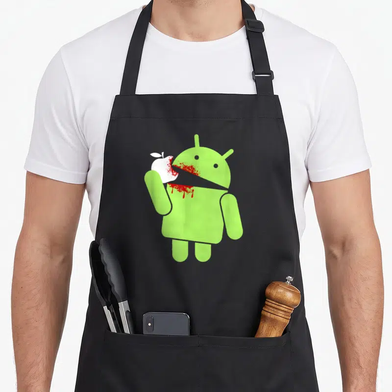 Tablier de cuisine noir avec un robot vert mangeant une pomme blanche tachée de rouge vif.