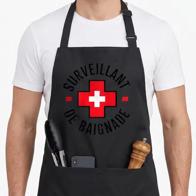 Tablier de cuisine noir avec une croix rouge et le texte Surveillant de Baignade en cercle.