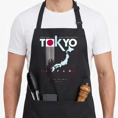 Tablier de cuisine noir avec une carte stylisée du Japon, le mot Tokyo et les noms de villes japonaises imprimés en blanc et rouge.