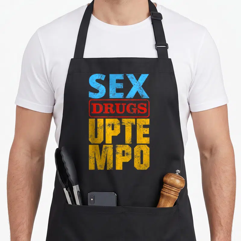 Tablier de cuisine noir avec texte Sex Drugs Uptempo en bleu rouge et jaune sur fond gris.
