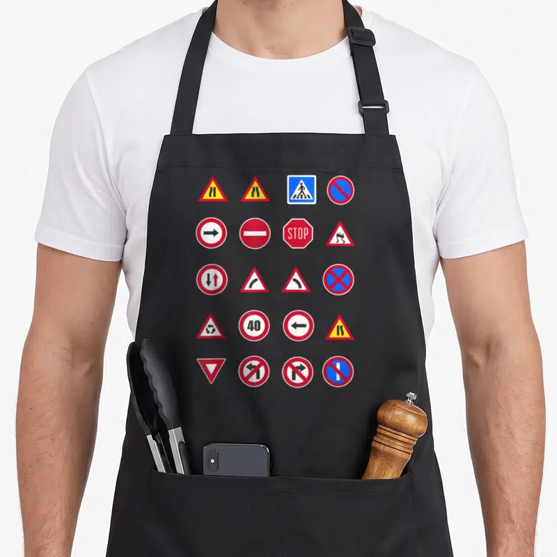 Tablier de cuisine noir avec une collection de panneaux de signalisation routière colorés imprimés sur le devant.