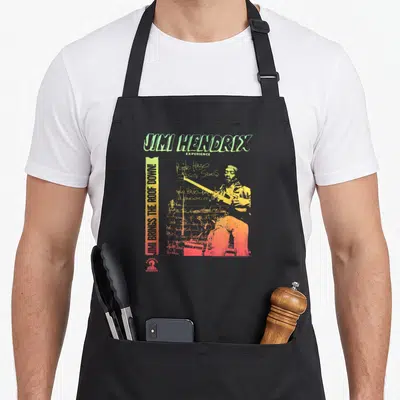 Tablier de cuisine noir avec illustration colorée de Jimi Hendrix et texte vertical Brings the Roof Down.
