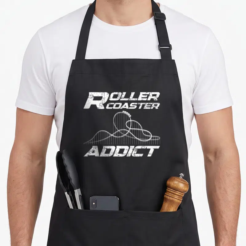 Tablier de cuisine noir avec inscription roller coaster addict et dessin de voie de montagnes russes en blanc.