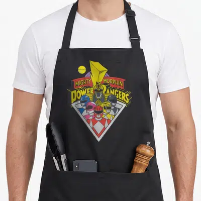 Tablier de cuisine noir avec le logo Mighty Morphin Power Rangers et les casques des colorés.