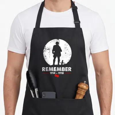 Tablier de cuisine noir avec silhouette soldat, texte Remember 1914-1918 et deux coquelicots rouges en bas du motif circulaire blanc.