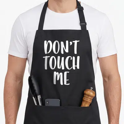 Tablier de cuisine noir avec l'inscription blanche Don't Touch Me en typographie manuscrite.