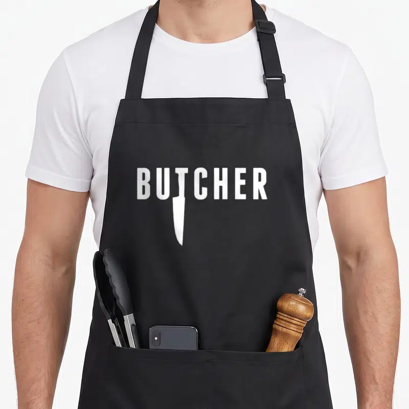 Tablier de cuisine noir avec le mot Butcher en blanc intégrant un couteau dans la typographie