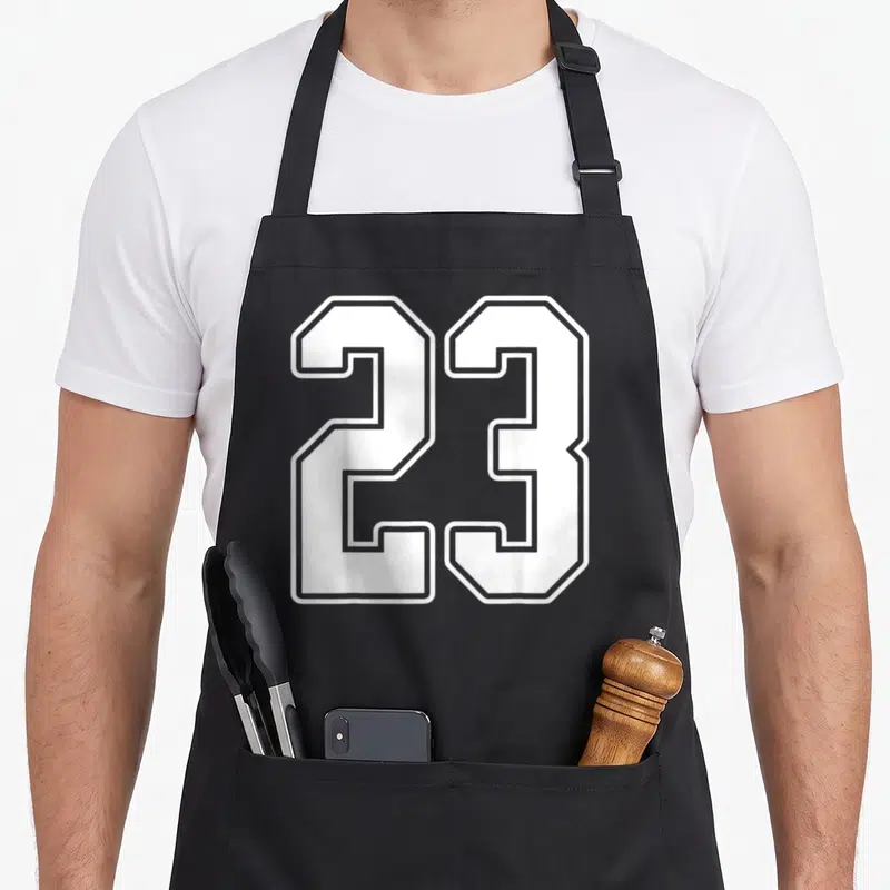 Tablier de cuisine noir avec le grand numéro 23 blanc stylisé maillot de sport sur le devant.